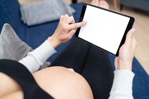 Young pregnant female using mobile device during relax in living room at home