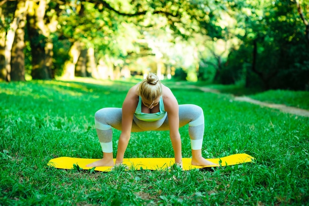 Young pregnant girl doing yoga in the park