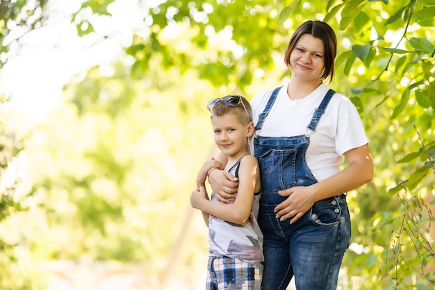 Young and pregnant mother with her son in summer park