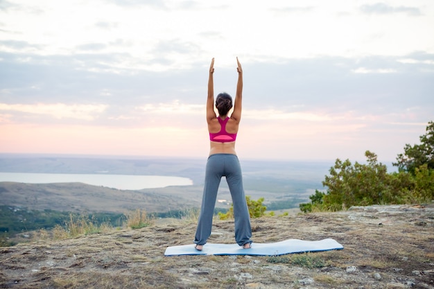 Young pregnant woman does yoga outdoors