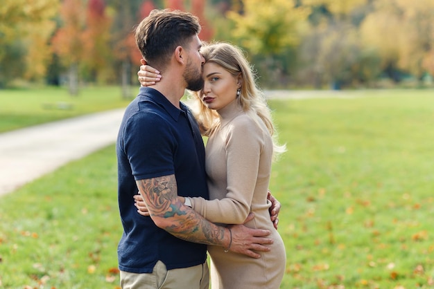 Young pregnant woman and her handsome husband are walking at the autumn park