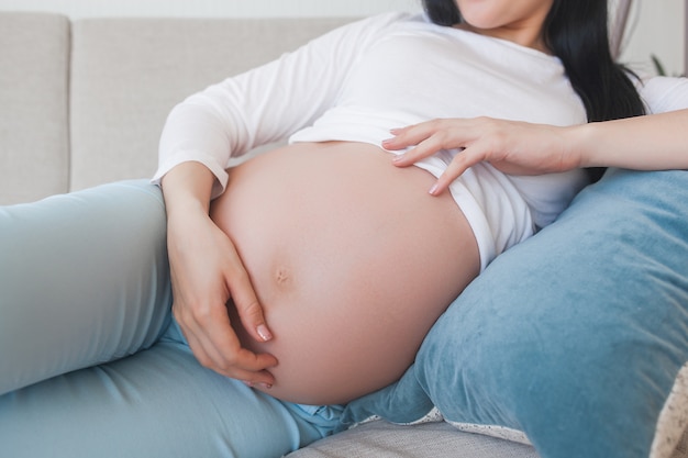 Young pregnant woman indoors. Closeup portrait of woman expecting. Beautiful female waiting for her little baby birth.