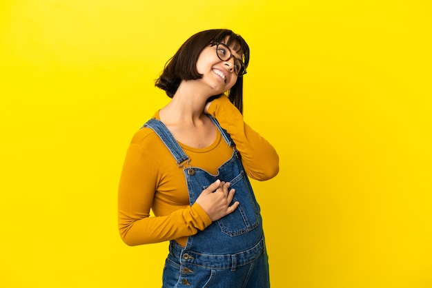 Young pregnant woman over isolated yellow background thinking an idea