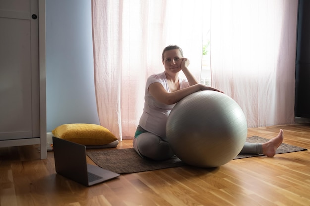 Young pregnant woman practices yoga at home