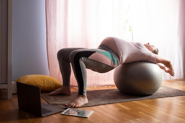 Young pregnant woman practices yoga at home