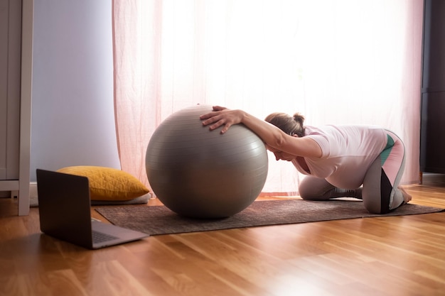 Young pregnant woman practices yoga at home