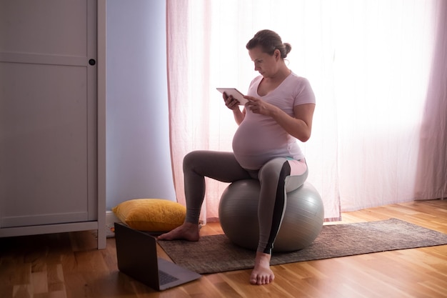 Young pregnant woman practices yoga at home