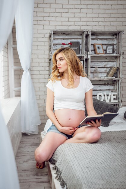 Young pregnant woman reading a book