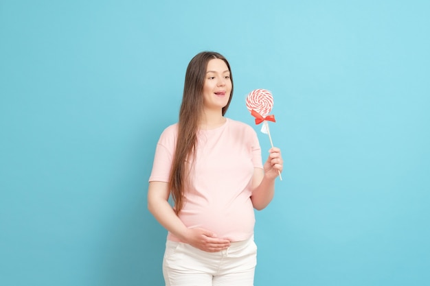 Young pregnant woman with candy in hand