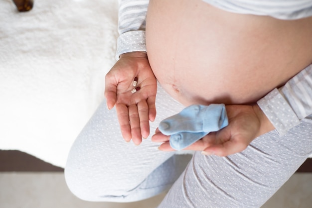 Young pregnant woman with pills at home.