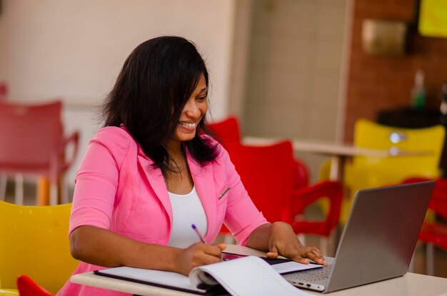 Young pretty african business woman smiling as she works in the office