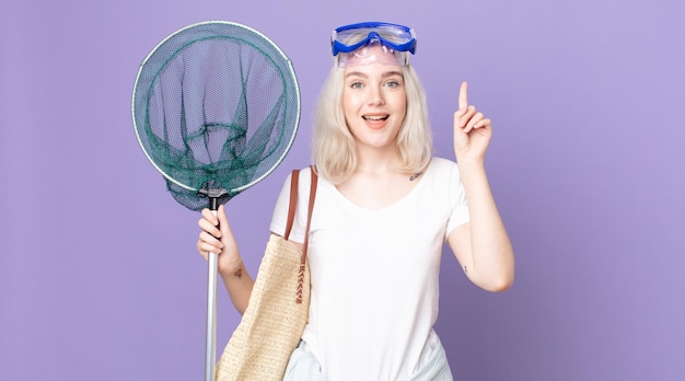 Young pretty albino woman feeling like a happy and excited genius after realizing an idea with goggles and a fishing net