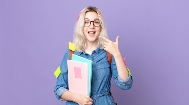 Young pretty albino woman looking excited and surprised pointing to the side. student concept