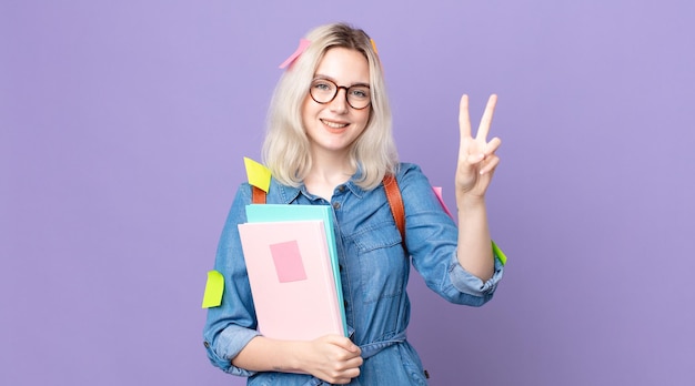 young pretty albino woman smiling and looking happy, gesturing victory or peace. student concept