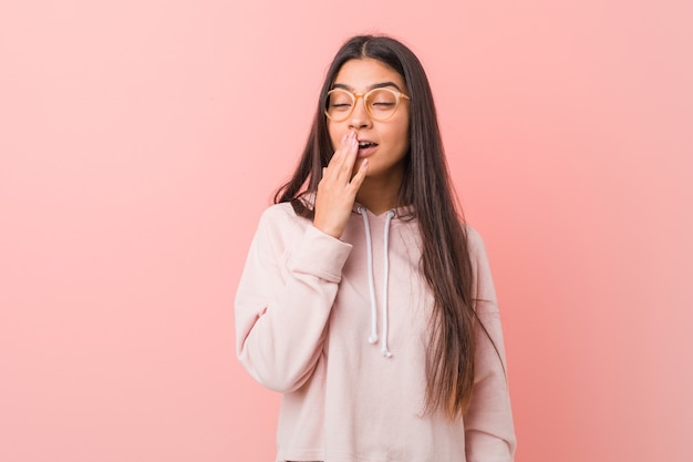 Young pretty arab woman wearing a casual sport look yawning showing a tired gesture covering mouth with hand.