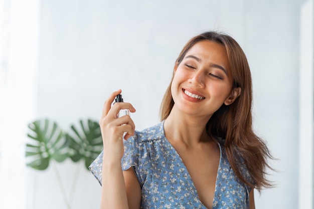 Young pretty Asian woman working as beauty vlogger using perfume