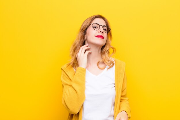 Young pretty blonde woman feeling stressed, frustrated and tired, rubbing painful neck, with a worried, troubled look against yellow wall