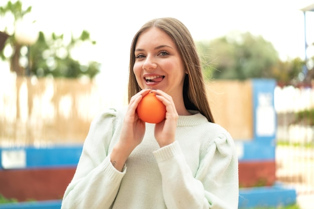 Young pretty blonde woman holding an orange with happy expression