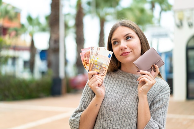 Young pretty blonde woman holding wallet and credit card