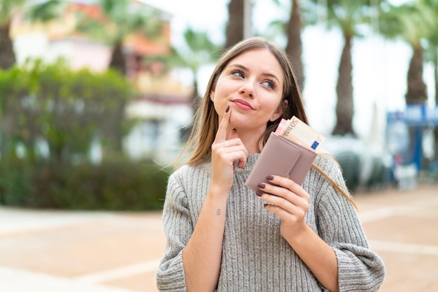 Young pretty blonde woman holding wallet with money