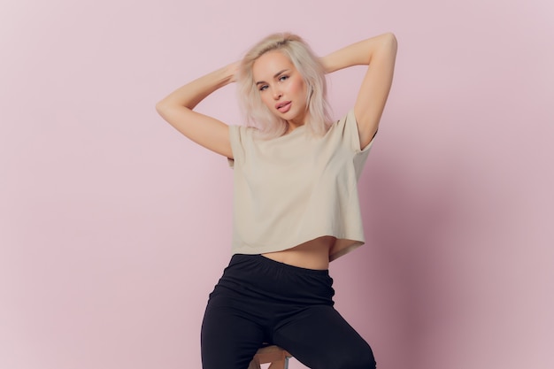 Young pretty blonde woman laughing happily with arms crossed, with a relaxed, positive and satisfied pose against pink flat wall.