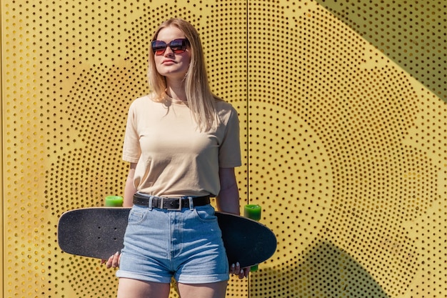 a young pretty blondie lady with skate board on the yellow and blue background