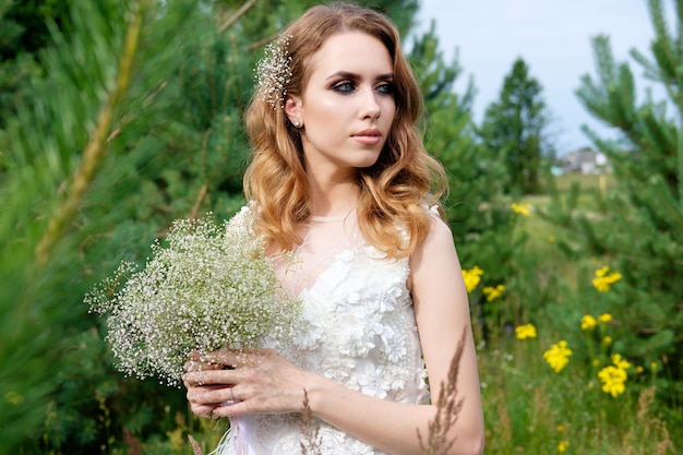 Young pretty bride in white wedding dress outdoors