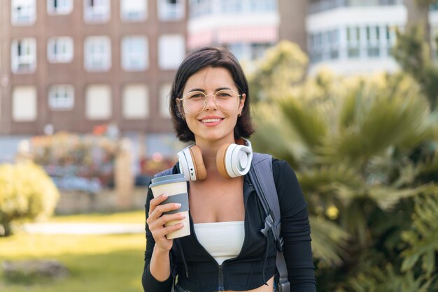 Young pretty Bulgarian woman at outdoors holding a take away coffee