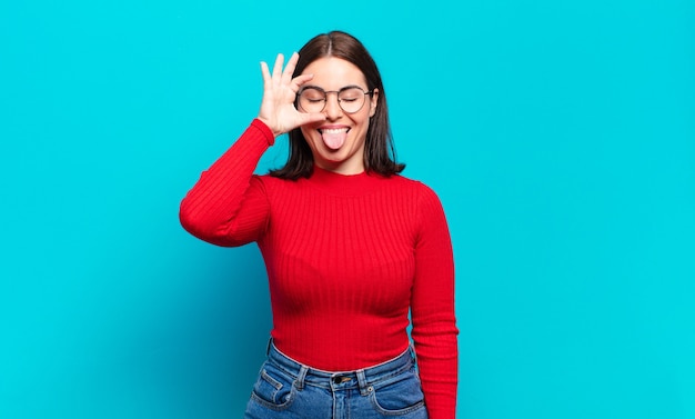 Young pretty casual woman smiling happily with funny face, joking and looking through peephole, spying on secrets