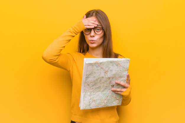 Young pretty caucasian woman worried and overwhelmed. She is holding a map.