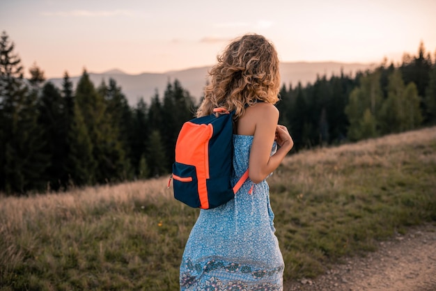 Young pretty curly woman sitting and enjoying on the mountains top Beautiful young cheerful female modelYoung woman outdoors Mountains land