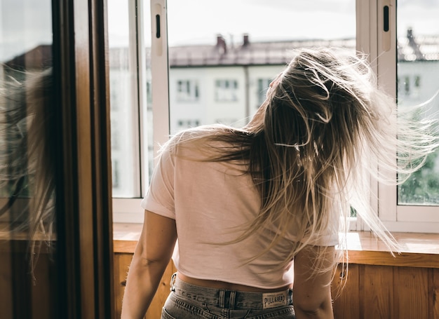 Young pretty dark-haired girl dancing at the window