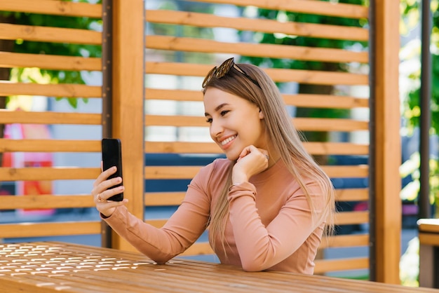 Young pretty female blogger is talking via video link or translation in an outdoor cafe