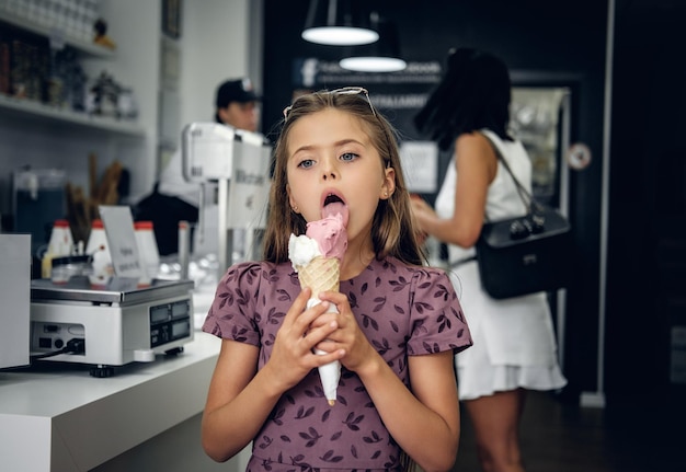 Young pretty girl in a dress, eating ice cream in a cafe.