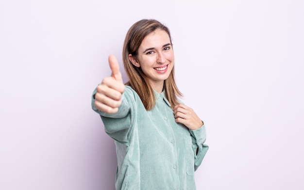 Young pretty girl feeling proud, carefree, confident and happy, smiling positively with thumbs up