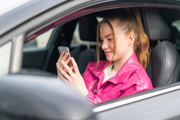 Young pretty girl inside a car using mobile phone