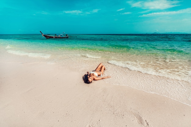 Young and pretty girl model in a bikini sunbathing on the beach resort of the Andaman sea