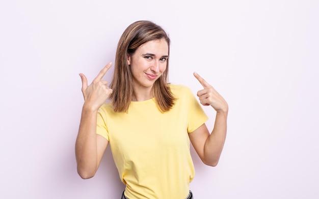 Young pretty girl with a bad attitude looking proud and aggressive, pointing upwards or making fun sign with hands