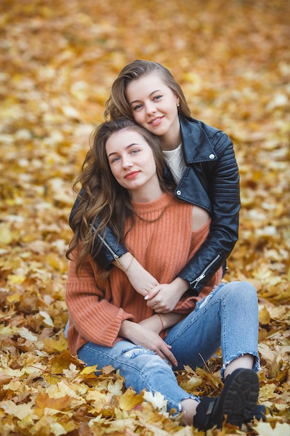 Young pretty girls having fun outdoors in autumn background. Cheerful friends in the fall time