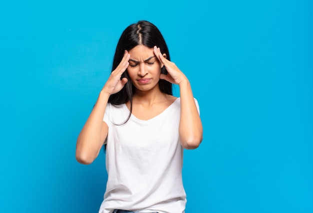 Young pretty hispanic woman looking stressed and frustrated, working under pressure with a headache and troubled with problems