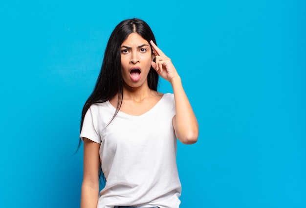 Young pretty hispanic woman looking surprised, open-mouthed, shocked, realizing a new thought, idea or concept