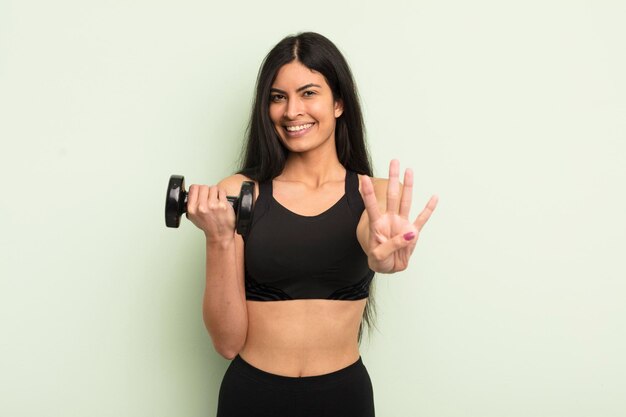 Young pretty hispanic woman smiling and looking friendly showing number four fitness concept