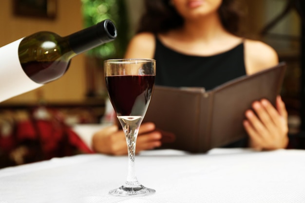 Young pretty lady at the restaurant. Waiter pouring wine in a glass