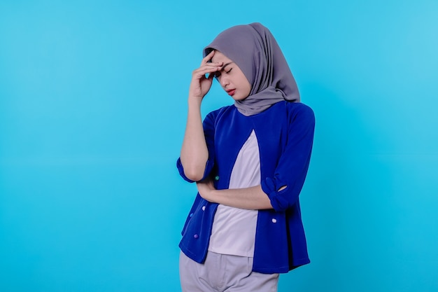 Young pretty latin woman looking concentrated and thinking hard on an idea, imagining a solution to a challenge or problem against blue wall