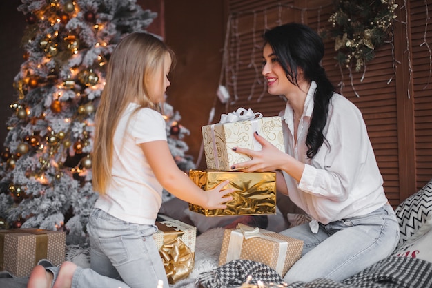 Young pretty mother and her little daughter sharing Christmas presents