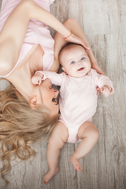 Young pretty mother with her little baby at home. Mom and daughter indoors.  month child with her parent in the bedroom.