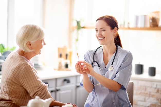 Young pretty nurse laughing before making injection