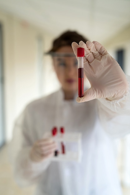 Young pretty nurse looking at a blood sample for diagnostic on Coronavirus or COVID19