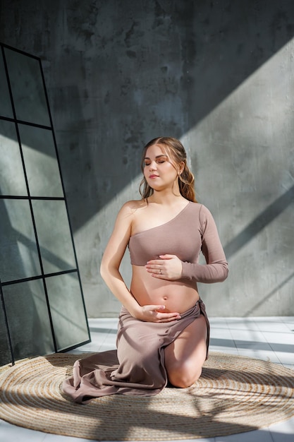 Young pretty pregnant woman in skirt posing in studio and stroking her belly Pregnant pregnant woman Happy pregnancy