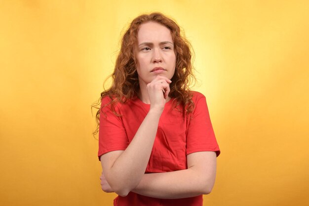 young pretty redhaired curly woman looking thoughtfully